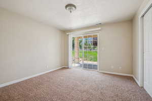 Carpeted empty room featuring a textured ceiling and baseboards