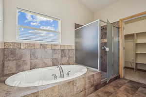 Full bathroom featuring a shower stall, a bath, and a walk in closet