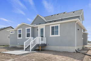 View of front facade featuring roof with shingles and stucco siding