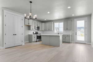 Kitchen featuring gray cabinetry, a textured ceiling, light countertops, appliances with stainless steel finishes, and hanging light fixtures