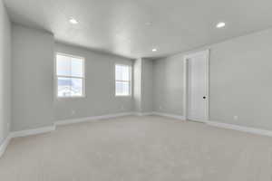 Spare room with light carpet, a textured ceiling, and recessed lighting