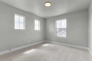 Carpeted empty room with baseboards and a textured ceiling