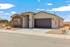 View of front of property featuring an attached garage, stucco siding, driveway, and a tile roof