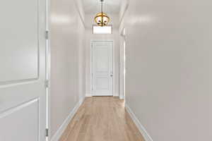Hallway with light wood-style flooring and a chandelier