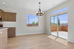 Kitchen with a chandelier, light wood-type flooring, light countertops, backsplash, and recessed lighting