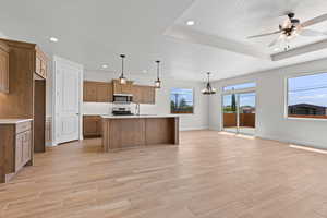 Kitchen featuring appliances with stainless steel finishes, open floor plan, light countertops, recessed lighting, and brown cabinets