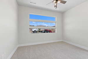 Carpeted empty room with a ceiling fan and baseboards