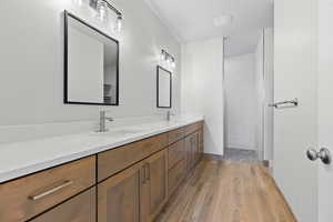 Full bath featuring double vanity, wood finished floors, and a tile shower