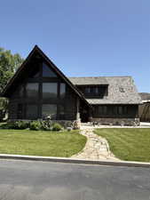 View of front of home featuring stone siding and a front lawn