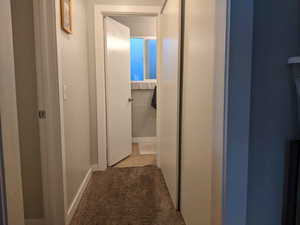 Hallway featuring light carpet and baseboards