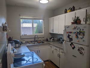 Kitchen featuring white appliances, white cabinetry, light countertops, and dark wood finished floors