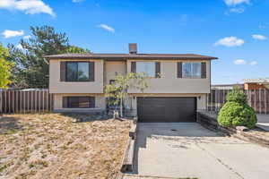 Raised ranch featuring an attached garage and concrete driveway