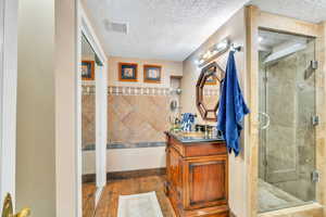 Bathroom with vanity, a stall shower, a textured ceiling, and dark wood-type flooring