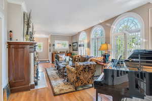 Living area with plenty of natural light, light wood-style floors, and ornamental molding