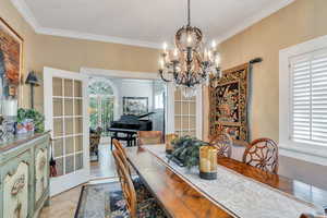 Dining area with a chandelier, crown molding, and french doors