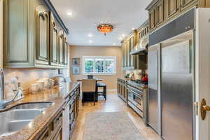 Kitchen featuring recessed lighting, premium appliances, dark stone countertops, and under cabinet range hood