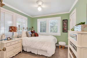 Carpeted bedroom featuring multiple windows and crown molding