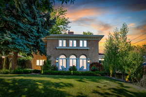 Italianate-style house featuring a chimney, a front lawn, and stucco siding