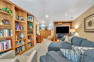 Living area with recessed lighting, a textured ceiling, and light carpet