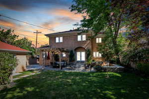 Back of property at dusk with a pergola, a patio, french doors, and stucco siding