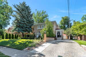 View of front facade with decorative driveway, stucco siding, and a front yard