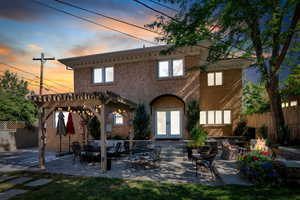 Rear view of house featuring french doors, a pergola, stucco siding, a patio area, and an outdoor living space