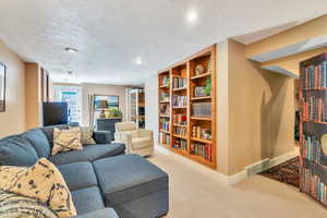 Living room featuring a textured ceiling, recessed lighting, built in features, and light carpet