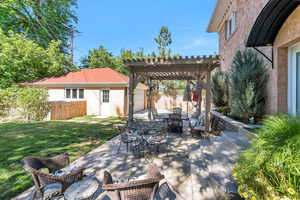 View of patio / terrace with a pergola, outdoor dining space, a garage, and an outbuilding