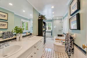 Bathroom featuring a bath, double vanity, a stall shower, ornamental molding, and recessed lighting