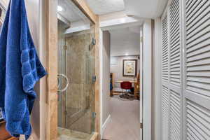 Bathroom with a textured ceiling, a stall shower, a closet, and carpet floors