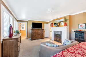 Carpeted bedroom with a fireplace with flush hearth and ornamental molding