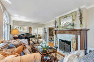 Living area with crown molding, plenty of natural light, a tile fireplace, and wood finished floors