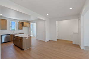 Kitchen with light countertops, light wood-style floors, stainless steel dishwasher, recessed lighting, and a center island