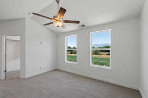 Spare room featuring light carpet, a ceiling fan, and vaulted ceiling