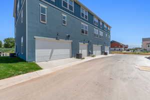 Back of house with board and batten siding, an attached garage, and stucco siding