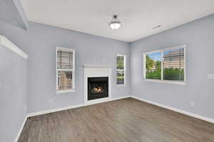 Unfurnished living room featuring wood finished floors and a lit fireplace