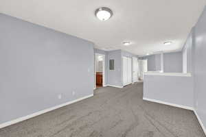 Carpeted spare room with baseboards and electric panel