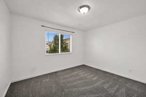 Unfurnished room featuring dark carpet and baseboards