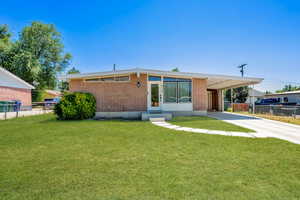 Grass enhanced- Mid-century modern home featuring concrete driveway, a carport, entry steps, and brick siding