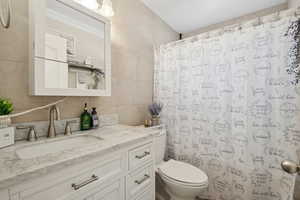 Bathroom with tile walls, vanity, a shower with curtain, and tasteful backsplash
