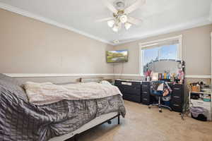 Bedroom with light colored carpet, ornamental molding, and ceiling fan