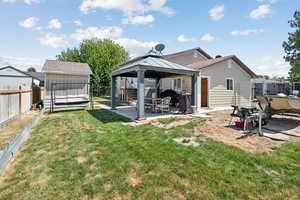 Rear view of property featuring a patio, a gazebo, a fenced backyard, and a storage shed