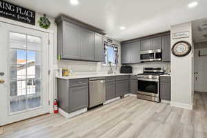 Kitchen featuring stainless steel appliances, gray cabinetry, light wood-style flooring, light countertops, and recessed lighting