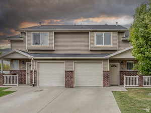 Multi unit property with brick siding, covered porch, and a garage
