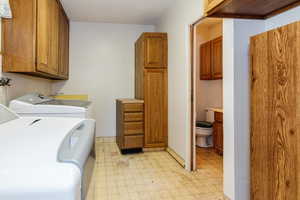 Washroom with light floors, cabinet space, and separate washer and dryer