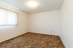 Carpeted empty room featuring baseboards