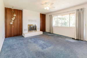 Unfurnished living room with ceiling fan, carpet flooring, and a fireplace