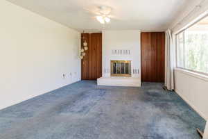 Unfurnished living room with a ceiling fan, a fireplace, and carpet