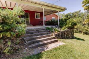 Doorway to property with a porch and a yard