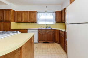 Kitchen with white appliances, light flooring, and brown cabinets